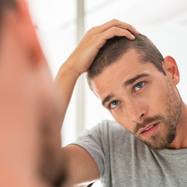 Young man checking hair in mirror