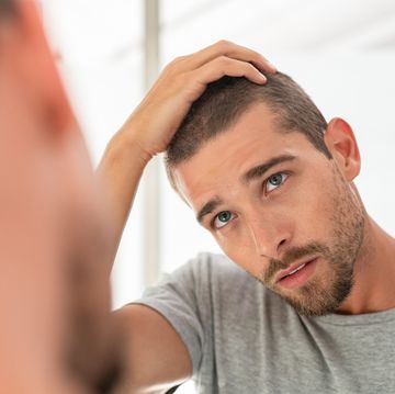 Young man checking hair in mirror