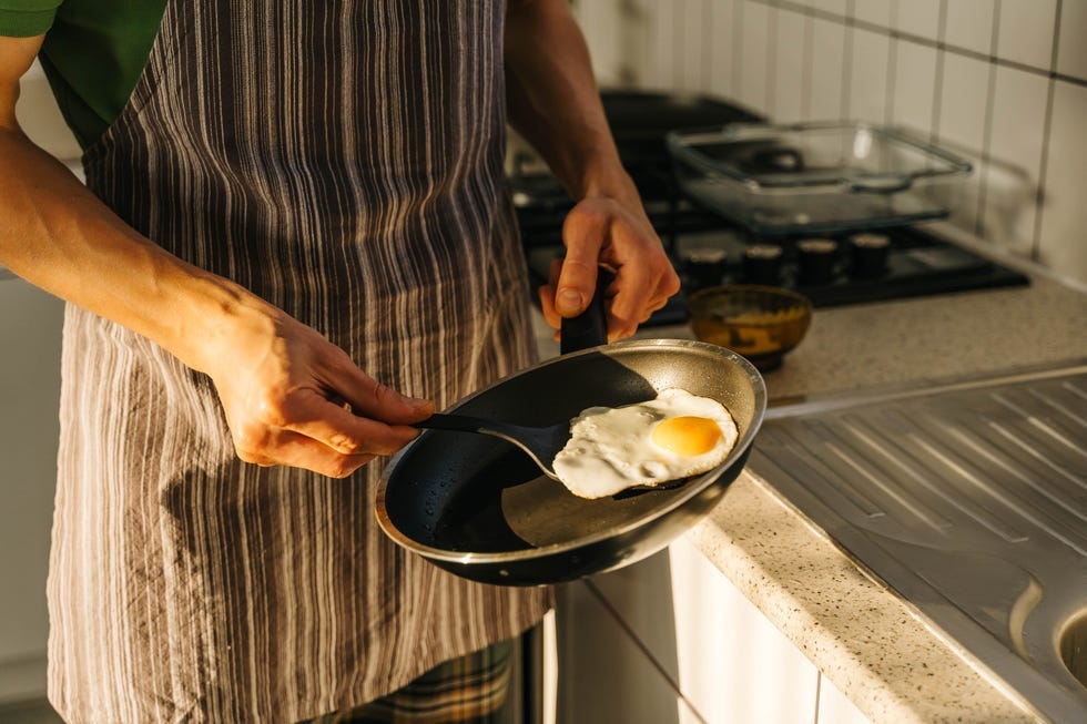 cook preparing a fried egg on a spatula in a kitchen setting