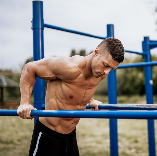 man motivating friend doing squats, lifting kettlebells in gym