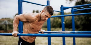 man motivating friend doing squats, lifting kettlebells in gym