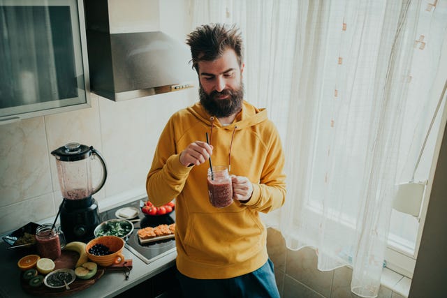 young man drinking smoothie for breakfast in the kitchen