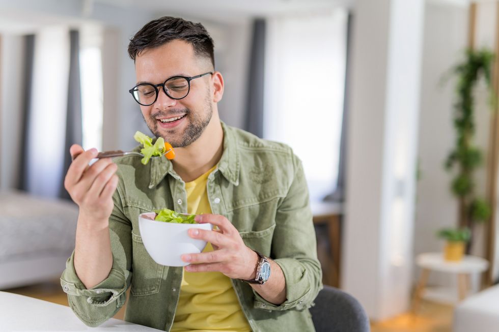 young man eating a salad at home