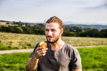 young man eating an apple in rural landscape