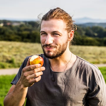 young man eating an apple in rural landscape