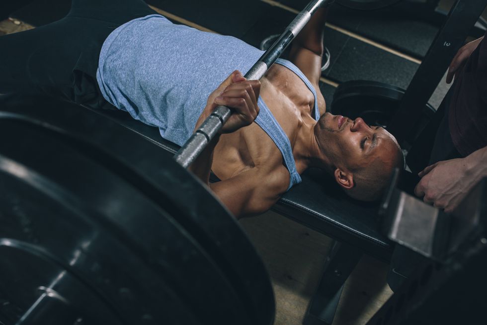 young man exercising bench press in gym