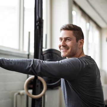 young man exercising with barbell at gym
