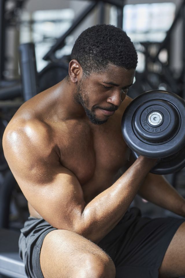 young man exercising with dumbbell in gym