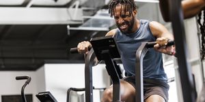 young man grimacing while exercising on bike at health club