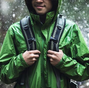 young man hiking in rain with waterproof jacket