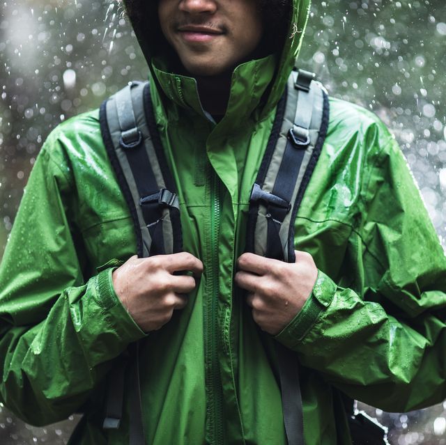 young man hiking in rain with waterproof jacket