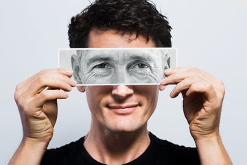 young man holding picture of old eyes over his