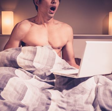 young man in bed watching pornography on laptop