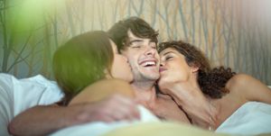 Young man in bed with two young women