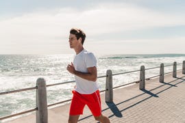 young man jogging on promenade at beach