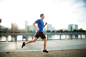 young man jogging on promenade in city