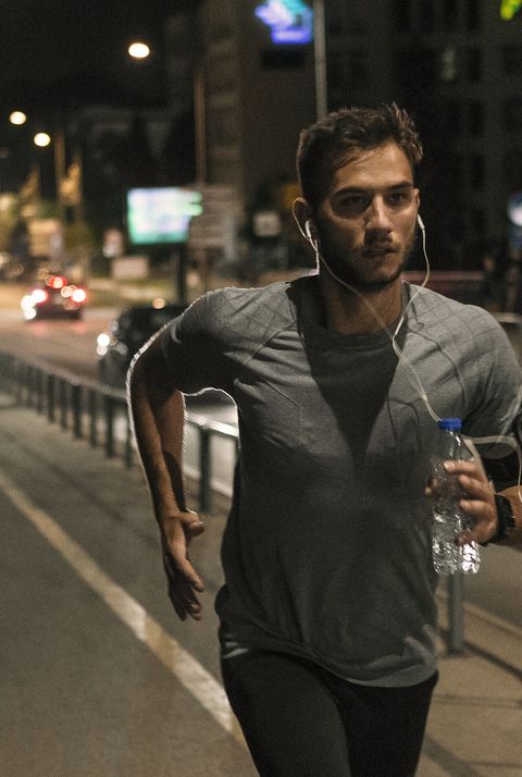 young man jogging through the city at night