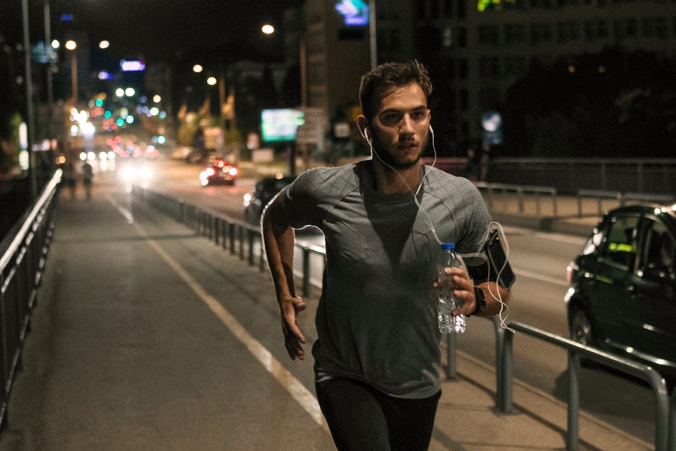 young man jogging through the city at night