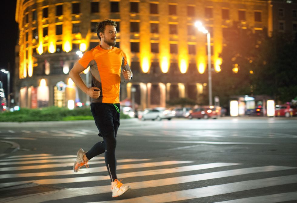 Young man jogging through the city at night.