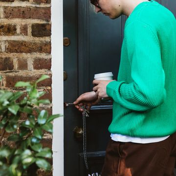 a young man leaving home in the morning, locking the door with his keys