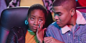 Young man looking at woman crying while watching movie in theater