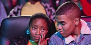young man looking at woman crying while watching movie in theater