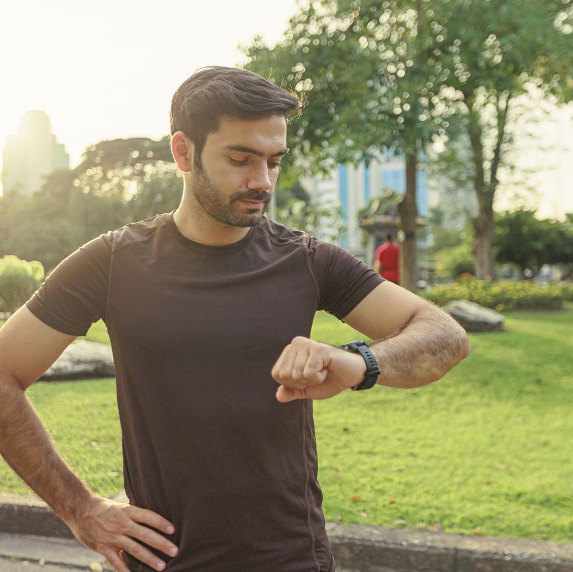 young man looking on watch before workout in public park for urban healthy lifestyle concept.