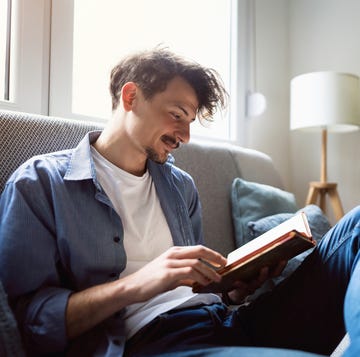 young man reading a book at home