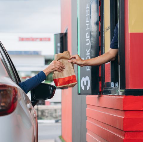 young man receiving coffee at drive thru counter, drive thru and take away for protect covid19