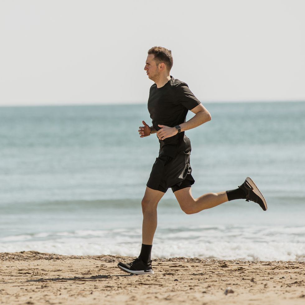 young man running at beach during sunny day