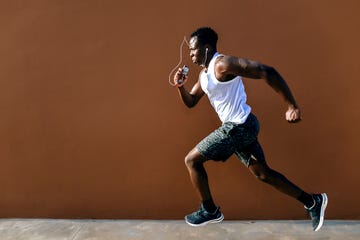 young man running in front of brown wall