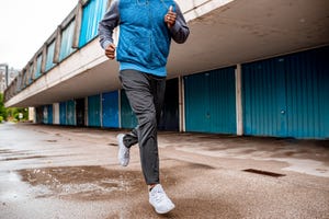 young man running over the puddle by the garages