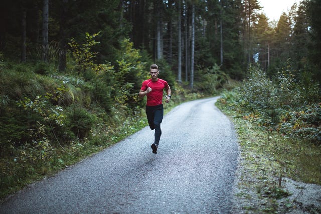 young man runs in pine forest at sunrise
