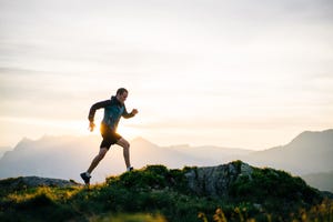 young man runs on mountain ridge at sunrise