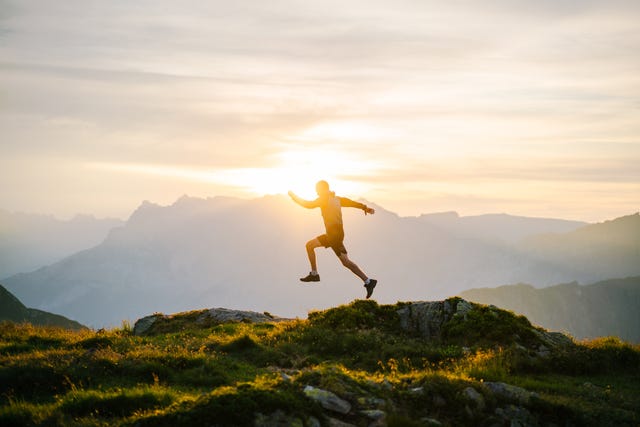 young man runs on mountain ridge at sunrise