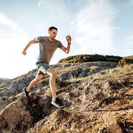 young man runs on mountain ridge