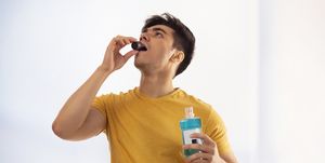 young man sipping from a cap of mouthwash in bathroom