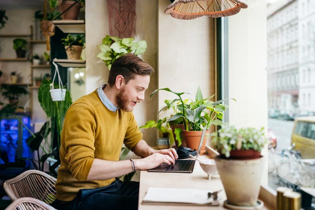 young man sitting in café using laptop