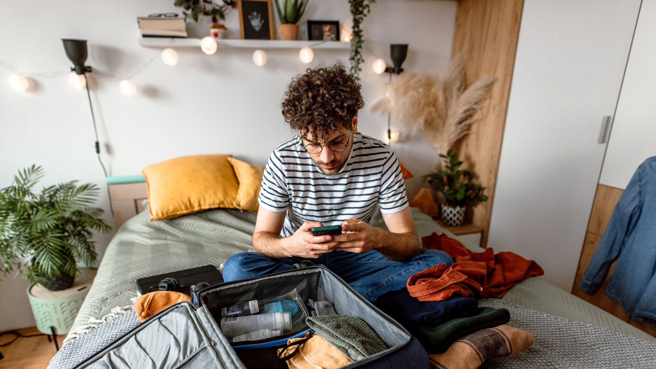 https://hips.hearstapps.com/hmg-prod/images/young-man-sitting-on-his-bed-using-smart-phone-and-royalty-free-image-1699627779.jpg?crop=1xw:0.84335xh;center,top
