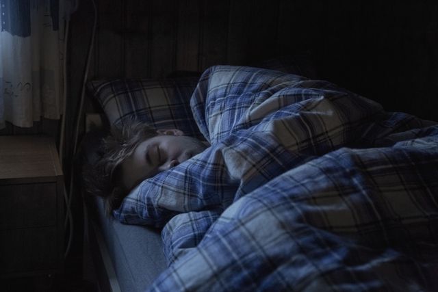 young man sleeping with blue plaid blanket