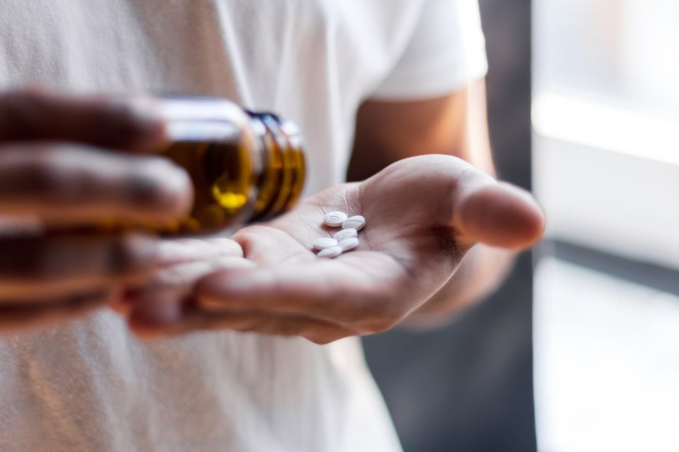 young man spilling multiple pills in his hand
