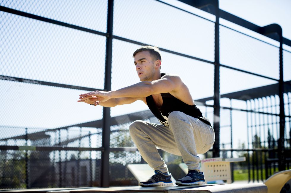 young man squatting outdoors