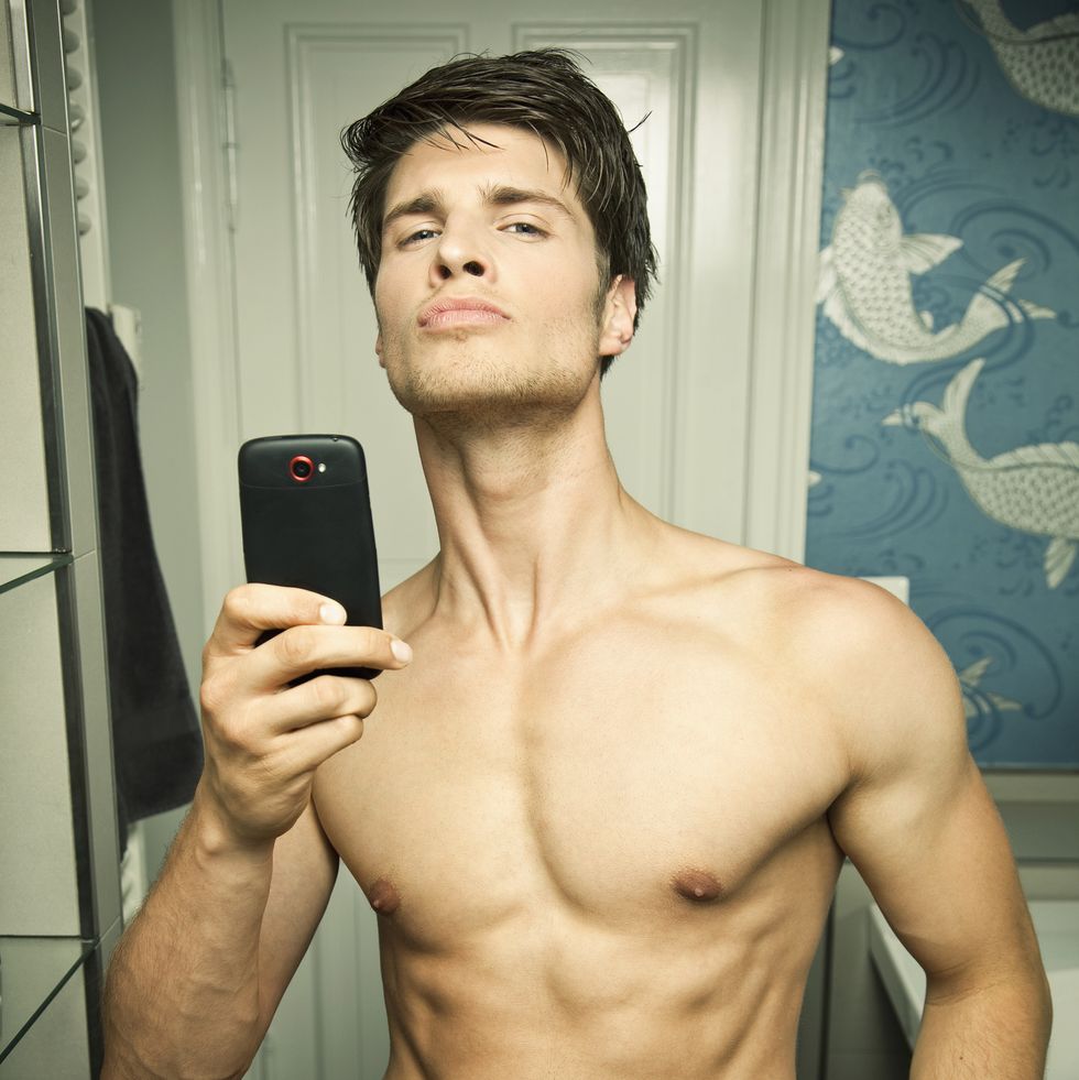 young man taking picture of himself by mobile in mirror
