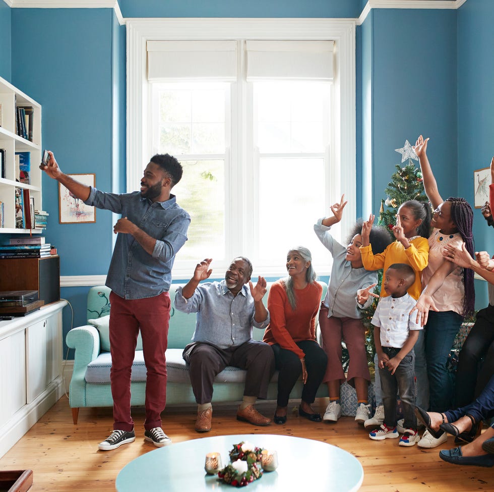 Young man taking selfie with family and friends a young black man taking a selfie in a living room surrounded by family and friends