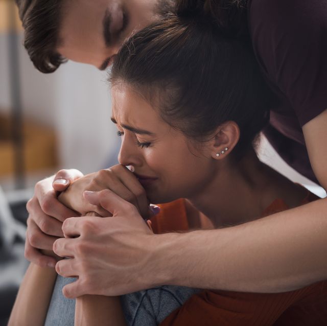 young man touching hands and kissing head of crying, depressed woman