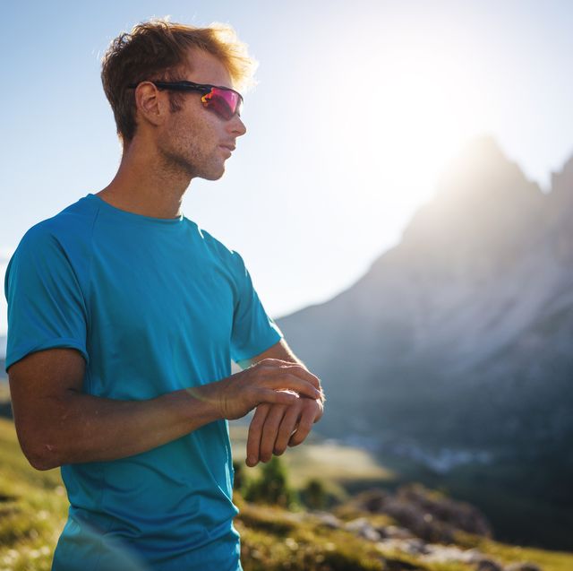 young man trail running on the mountain, looking sport watch