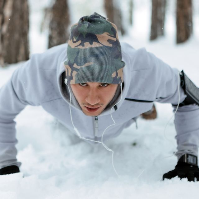 young man training in snow doing pushups