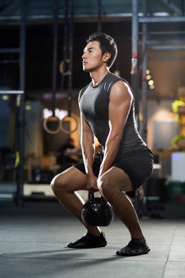 Young man training with kettlebell in gym gym