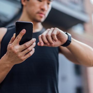 young man using fitness app on smart phone and smart watch for tracking workout