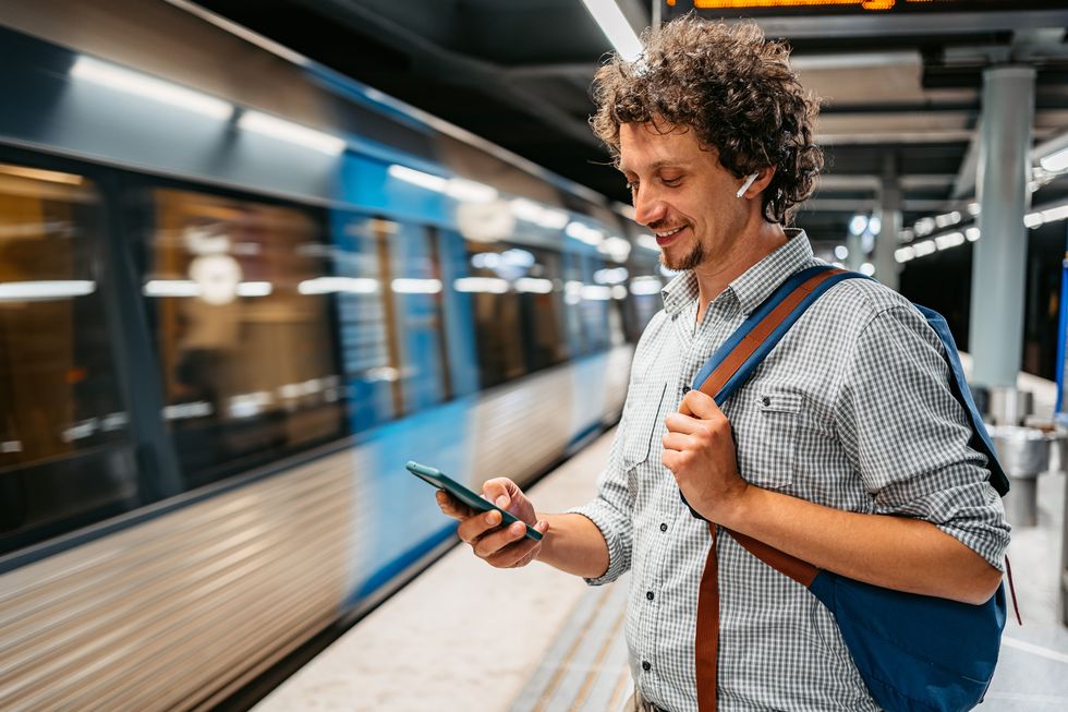 young man using phone while waiting for a subway train in stockholm